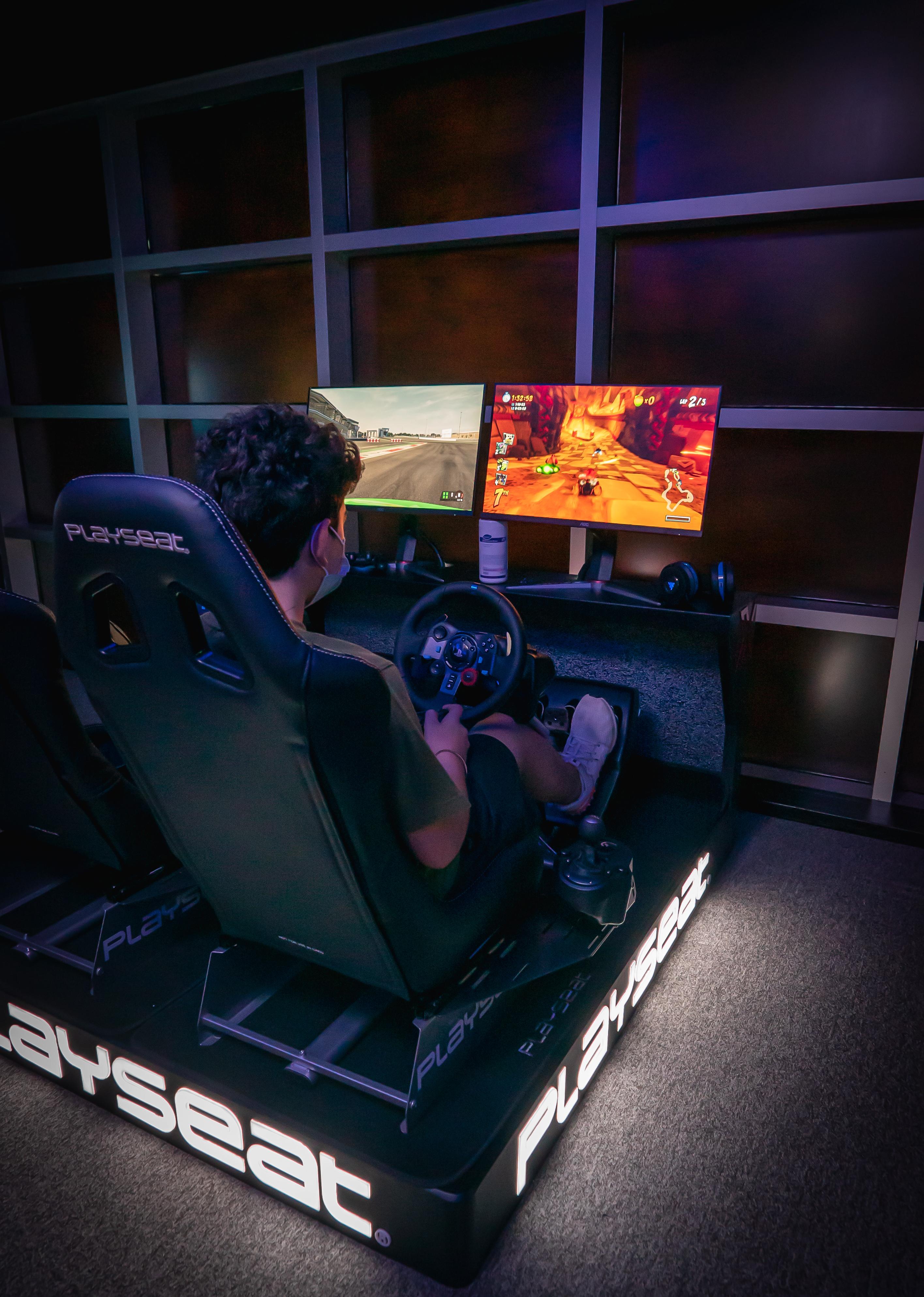 Grand Cosmopolitan Hotel Dubai Exterior foto The photo shows a person sitting in a racing gaming chair equipped with a steering wheel and pedals. They are facing two computer monitors. One monitor displays a racing simulation, while the other appears to show a different game or racing scene. Th