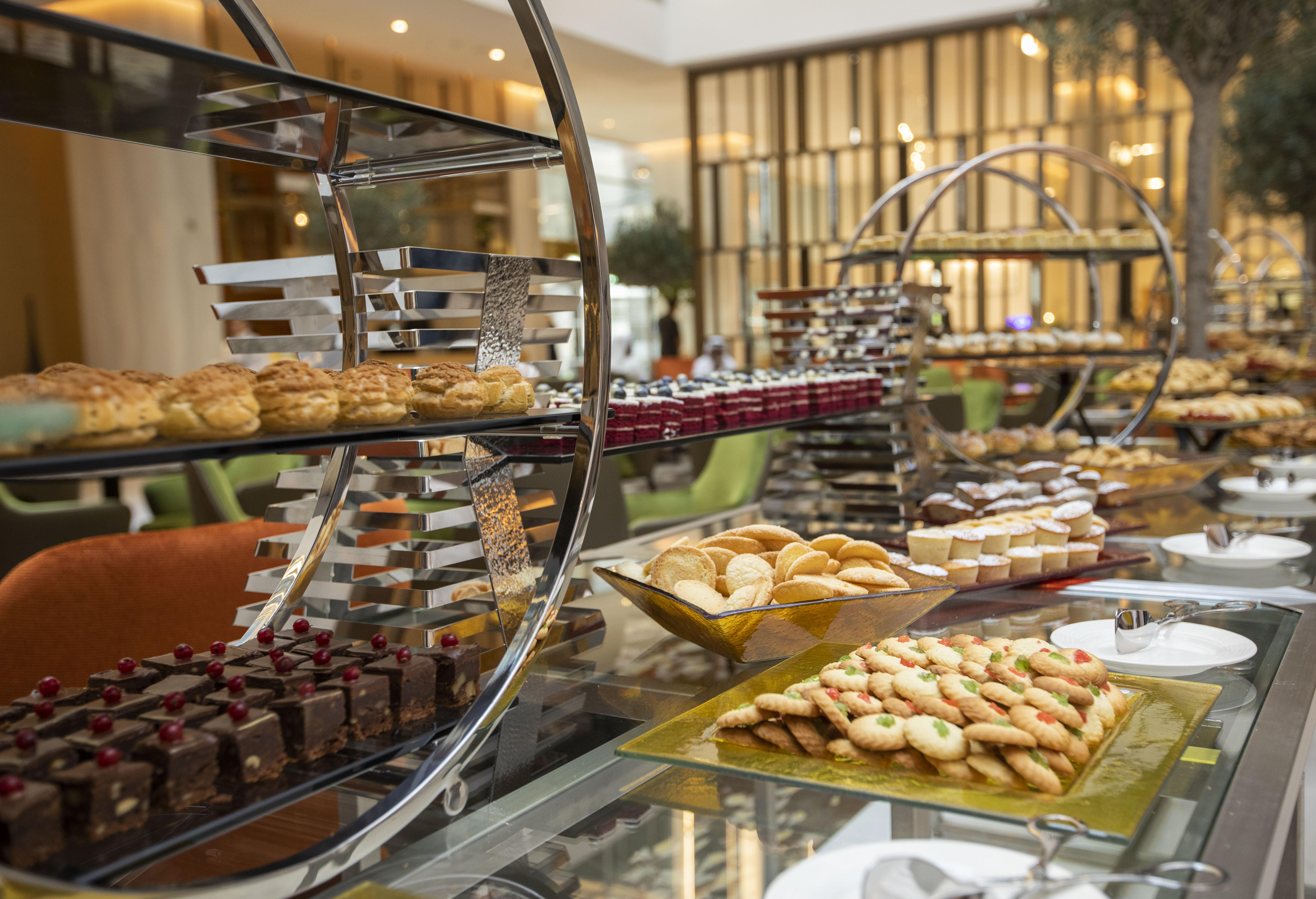 Grand Cosmopolitan Hotel Dubai Exterior foto The photo showcases an elegant dessert display featuring a variety of baked goods. There are multiple tiers of treats, including pastries, cookies, and chocolates. On the lower tier, there appears to be an assortment of cookies arranged on a rectangu