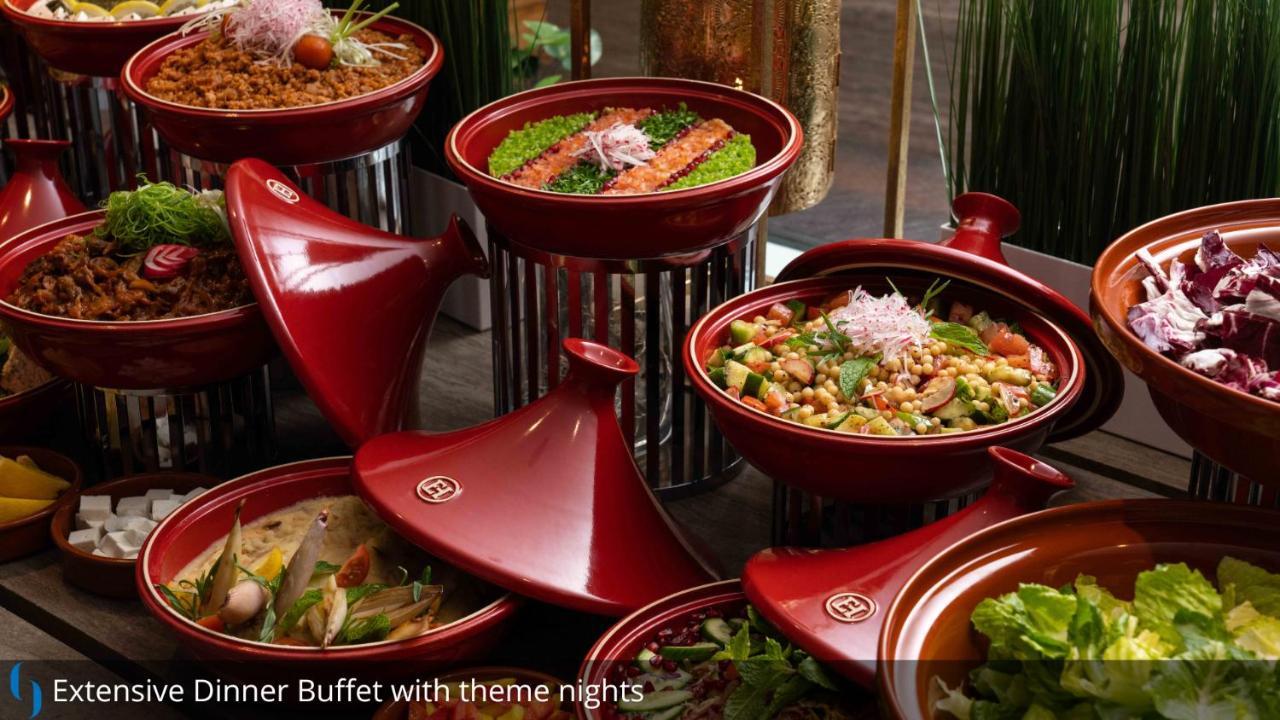Grand Cosmopolitan Hotel Dubai Exterior foto The photo displays an assortment of colorful dishes arranged in red ceramic containers. Each dish appears to have various ingredients, likely featuring a mix of vegetables, proteins, and grains. The presentation is visually appealing, with vibrant gr