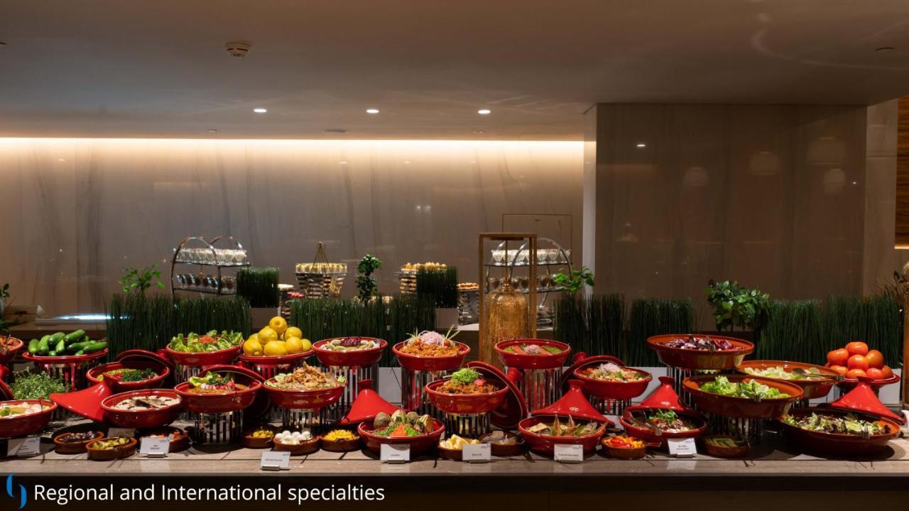 Grand Cosmopolitan Hotel Dubai Exterior foto The photo displays a buffet setup featuring a variety of dishes arranged in decorative baskets. There are multiple red baskets filled with a range of colorful dishes, including salads, fruits, and other culinary specialties. The background has a mode